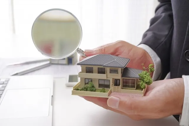 手のひらに乗る住宅模型と拡大鏡